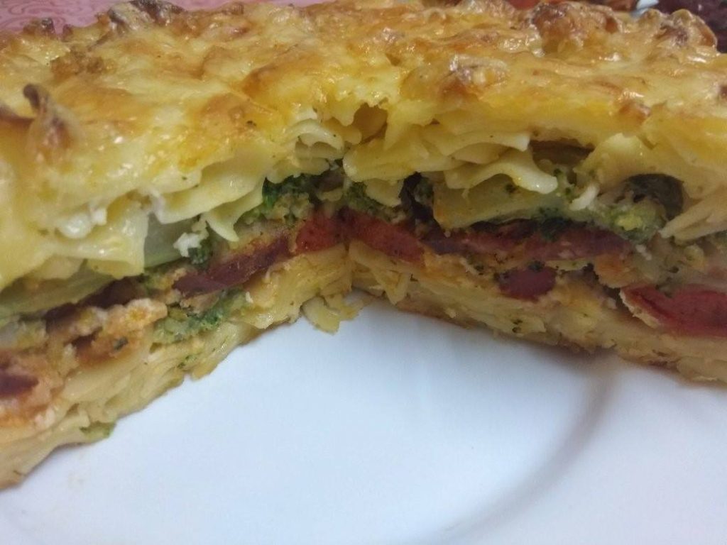 Fele tésztát belerakom és rakok rá kolbászt vagy más húsfélét. Rárakom a brokkolit, ha akarom szórhatok rá sajtot. Megöntözöm a tojásos tejföl több mint felével.