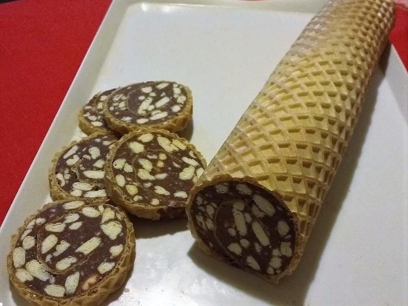 A tejet a cukorral főni teszem, amikor felforrt, hozzáadom a kakaóport és a rum aromát. Lehúzom a tűzről, beleteszem a vajat, beleöntöm a darált és a tördelt kekszet. Összekeverem, majd ezt a krémet még forrón az ostyalapokra kenem. 2-3 percig rajta hagyom, hogy a lapok kicsit puhuljanak, majd óvatosan, szorosan feltekerem, és hagyom őket teljesen kihűlni. Összesen két rudat készítsünk belőle.