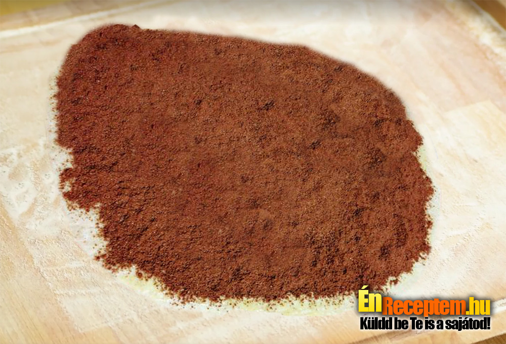 A tésztát két részre osztjuk. Lisztezett felületen vékonyra sodorjuk. Megkenjük olvasztott margarinnal és rászórjuk a kakaóval elkevert cukrot.