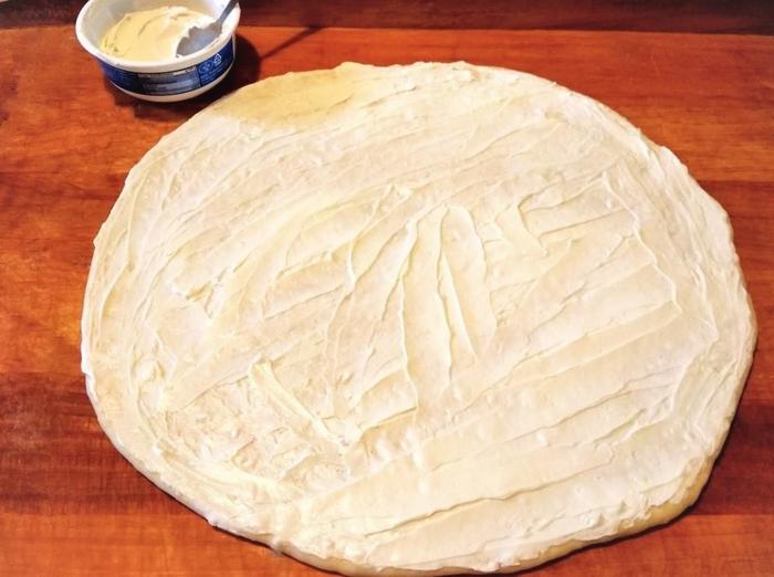 Rászórjuk az aprított medvehagymát. 16 cikkre vágjuk, és feltekerjük kifliknek.